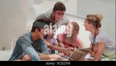 Collaborating study group typing, discussing in study lounge, with laptop, notebooks Stock Photo