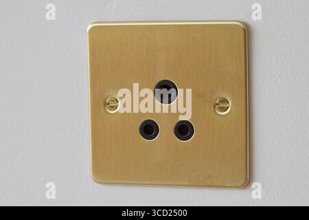 Brushed brass surface of a 5 amp electrical socket in the United Kingdom. Stock Photo