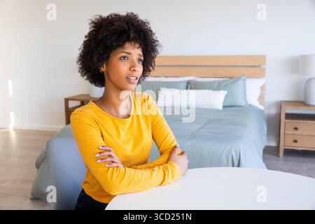 Woman sitting at round white table in bedroom with light blue duvet plus ceramic lamp Stock Photo