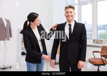 Tailor measuring jacket on man in atelier Stock Photo