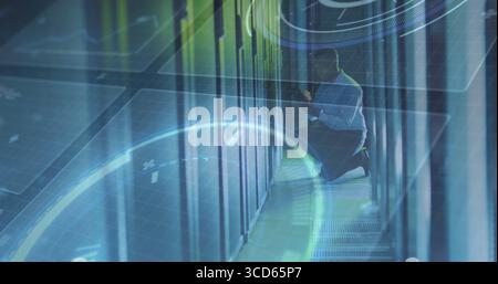 Kneeling technician in shirt examining servers in data center aisle, with HUD overlays Stock Photo