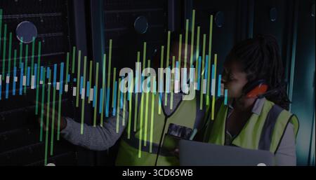 Two technicians in safety gear inspecting server racks in data center, with laptop, data overlay Stock Photo