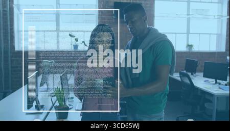 Collaborating software developers reviewing code and charts at open-plan office, with dual monitors Stock Photo