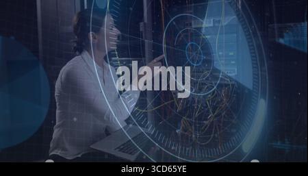 Kneeling technician pointing laptop at rack in server room monitoring holographic UI, copy space Stock Photo