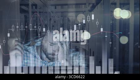 Analyzing engineer wearing plaid shirt taking notes at server room desk, with bar charts Stock Photo
