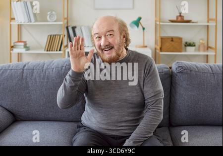 Senior man waves hello, having video call on laptop talking with relatives, smiling aged grandfather Stock Photo