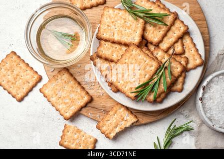 Olive oil salty crackers with rosemary on wooden platter, top view. Homemade cripsy crackers with sea salt and herbs. Stock Photo