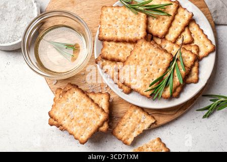 Olive oil salty crackers with rosemary on wooden platter, top view. Homemade cripsy crackers with sea salt and herbs. Stock Photo