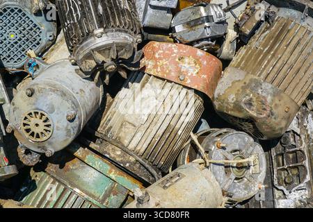 Close-up of worn and corroded electric motors piled for recycling, showing rust, paint wear, and industrial metal textures Stock Photo
