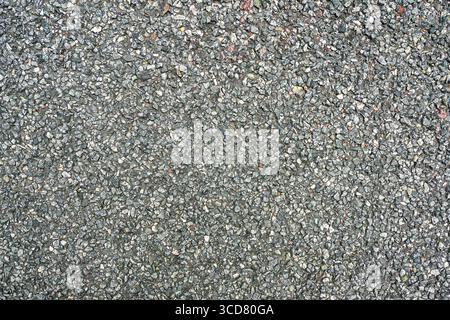 Detailed close-up of rough asphalt pavement with small gravel stones, ideal for background or texture use Stock Photo