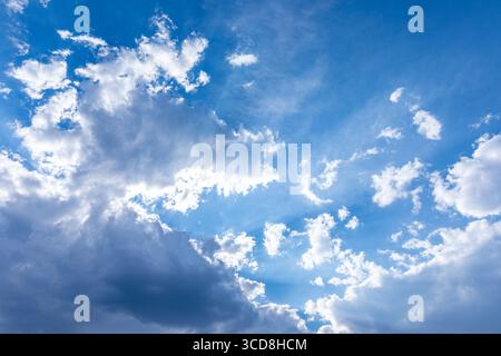 Vivid blue sky filled with soft, white cumulus clouds, creating a bright and uplifting natural backdrop suitable for diverse creative uses. Stock Photo
