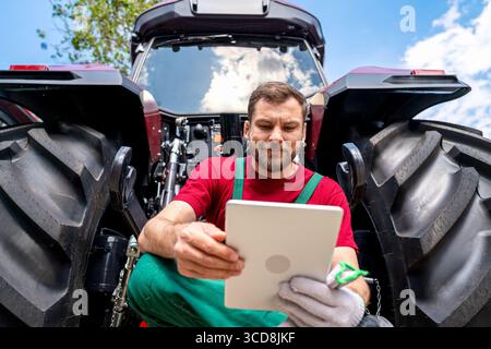Male farmer using digital tablet near the tractor Stock Photo