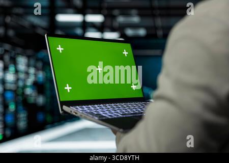 Close up of server farm software developer using mockup laptop to repair equipment storing datasets. IT specialist using green screen notebook to debug rackmounts doing computational operations Stock Photo