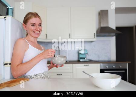 Cheerful woman cooking in modern kitchen interior Stock Photo