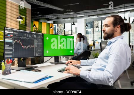Day trader using software on green screen PC to capitalize on market fluctuations when buying and selling stocks. Prop firm office worker uses chroma key computer to identify profit opportunities Stock Photo