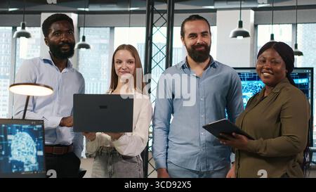 Portrait of teamworking programmers in office developing apps using AI automation. Team of smiling IT experts working on devices, debugging applications with artificial intelligence, camera A Stock Photo