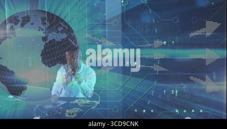 Holding yellow cables man in checkered shirt connecting circuit board at desk, with laptop graphics Stock Photo
