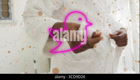 Mid adult woman adjusting bathrobe belt in bright bathing area, with neon pink bird overlay Stock Photo