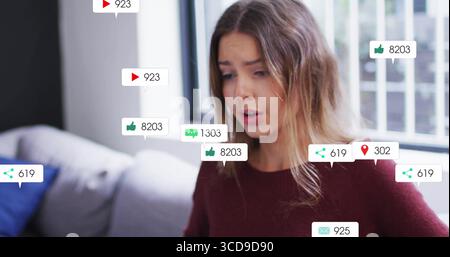 Sitting in burgundy sweater interacting with floating digital overlays on sofa at home, copy space Stock Photo