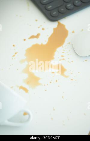 Coffee spill on white table with office supplies nearby Stock Photo
