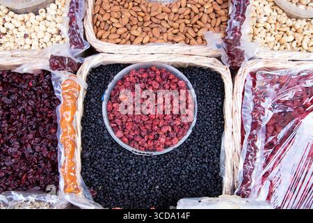 Variety of dried fruits and nuts displayed in wicker baskets at a market stall. Organic healthy snacks, natural ingredients for cooking and desserts. Stock Photo