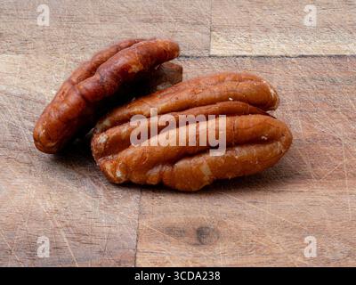Two tasty pecan nuts on brown chopping board Stock Photo
