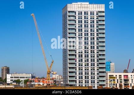 Residential new development high rise tower block with a crane in London against a cloudless sky Stock Photo