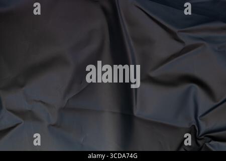 Black smooth folded lining fabric used in thermal bags, close-up view, texture for background or wallpaper Stock Photo