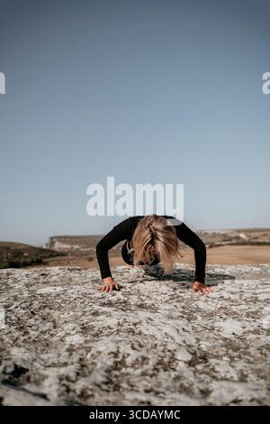 Woman Doing Push-Ups on a Rocky Cliff Stock Photo