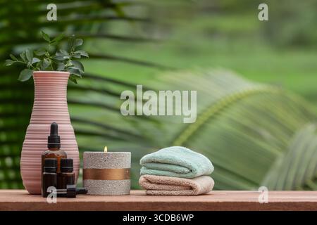 Items for spa and massage, towels and candles on wooden table. Zen and relax concept. Spa composition with treatment natural ingredients on green natu Stock Photo