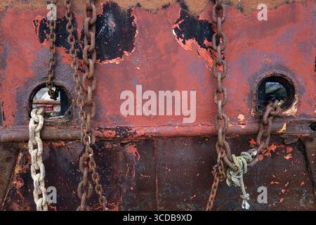 rusty metal and weathered red paint on old boat hull, norfolk, england Stock Photo