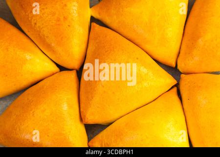 Homemade baked triangular buns lie on white parchment. Stock Photo