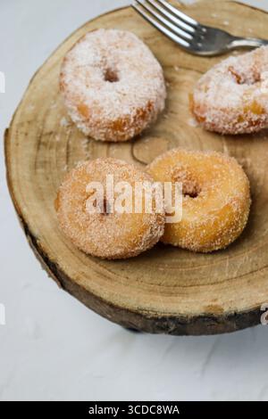 Four small golden fried donuts served on a wooden plate against a clean white background. Sweet mini pastries with a crispy exterior and soft inside, Stock Photo