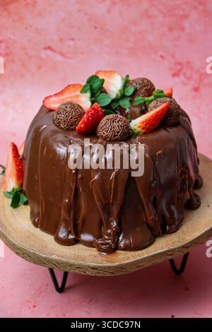 Delicious chocolate cake covered in rich chocolate ganache, decorated with fresh strawberries and chocolate truffles. Stock Photo