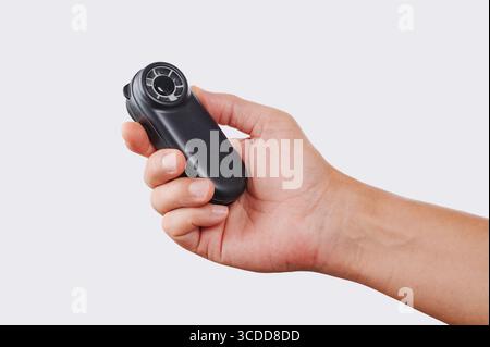 close-up of a man using a small battery-powered handheld fan to refresh himself while holding it sideways against a plain white studio background Stock Photo