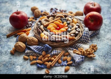 Composition of dried fruits and nuts in small wicker bowl placed on a stone table. Assortment contais almonds, walnuts, apricots, plums, figs, dates, Stock Photo
