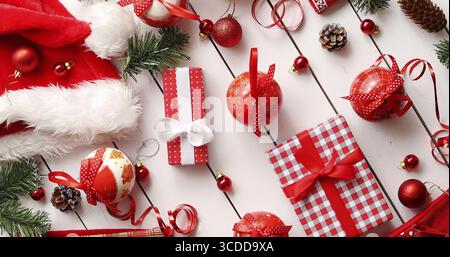 From above shot of assorted Christmas decorations lying on white timber tabletop near beautifully wrapped gift boxes Stock Photo