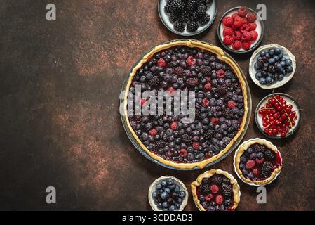 Homemade autumn sweet berry pie on dark rustic background. Served with fresh forest fruis. Top view, flat lay with copy space Stock Photo