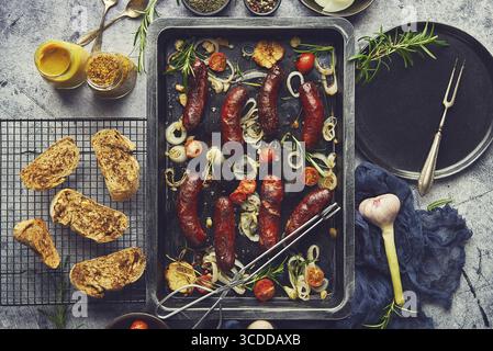 Delicious grilled sausages served on metal rusty tray. With barbecued vegetables, bread and mustard. Top view, flat lay Stock Photo
