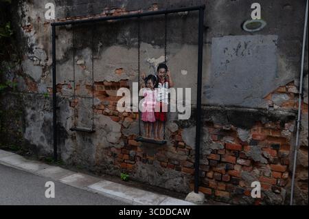 A wall mural of ‘Brother and Sidter’ on a real swing in Lebuh Chulia, (Chulia Street) by Malaysian artist Louis Gan in George Town, a city of Penang i Stock Photo
