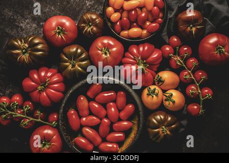 Various kinds of fresh tomatoes placed on dark rusty table. Top view, flat lay Stock Photo