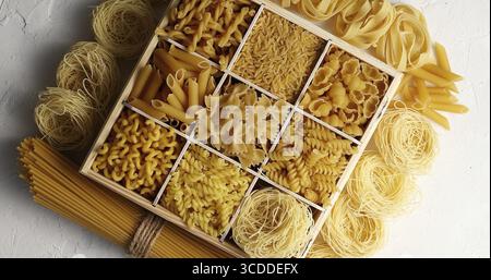 From above view of macaroni of different sort placed in dish with sections on white background Stock Photo
