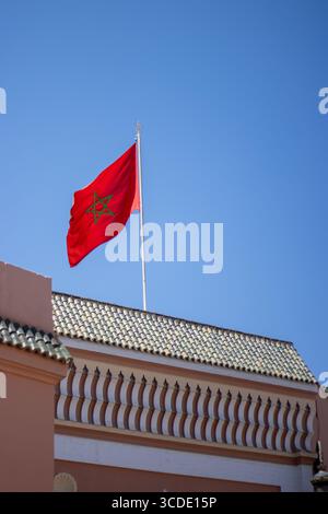 Moroccan flag flying against a clear blue sky above the souk market in the medina in Marrakesh, Morocco Stock Photo