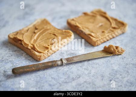 Two tasty peanut butter toasts placed on stone table. Knife on side. Above view Stock Photo