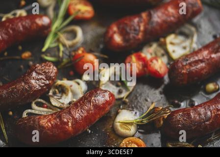 Delicious grilled sausages served on metal rusty tray. With barbecued vegetables, bread and mustard. Top view, flat lay Stock Photo