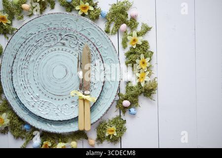 Easter table setting with flowers and eggs. Empty decorative ceramic plates. Rustical dishware. View from above Stock Photo
