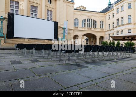 The open-air cinema set up in front of the historic building reflects the pre-show silence with its empty seats. Stock Photo