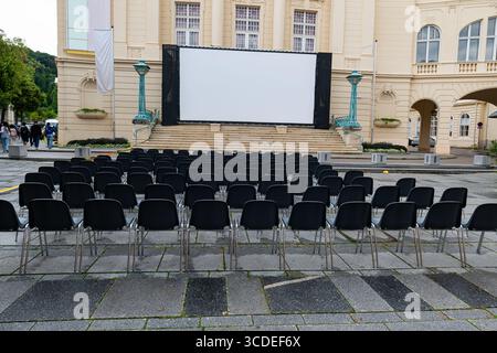 The open-air cinema set up in front of the historic building reflects the pre-show silence with its empty seats. Stock Photo
