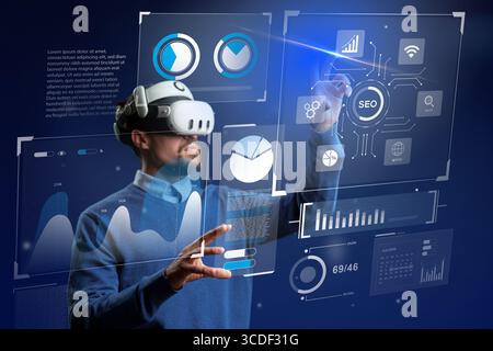 Man in virtual reality headset interacting with digital analytics display in modern workspace Stock Photo