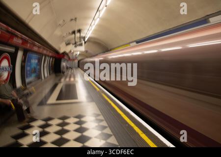 Motion-blurred Central Line train arriving at Holborn station on the London Underground, capturing speed, movement, and urban energy. Stock Photo